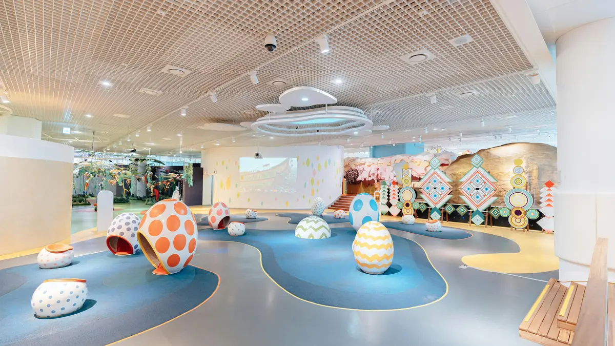 An indoor play space with egg-shaped soft-play pods on a curving blue-and-grey floor.